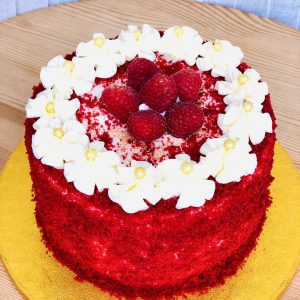 Gourmet red velvet celebration cake topped with fresh strawberries and icing flowers