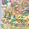 Colourful artisan childrens birthday cake with unicorn and lolly topping