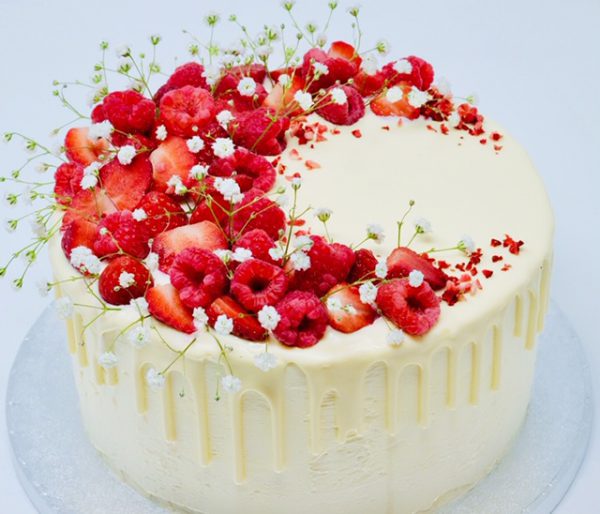 beautiful gourmet mothers day cake topped with flowers and raspberries
