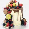 Handcrafted French fruit macaronia drip cake, topped with freshly baked macarons and fruits
