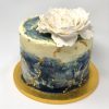 Unique galactic sparkle cake in blue, gold and white swirls topped with a flower