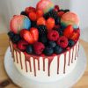 Top of freshly baked vanilla sponge cake with lots of fresh berries and handcrafted French macarons
