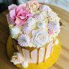 Top of gold drip effect handcrafted cake, decorated with baby pink roses and meringues