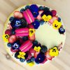 Colourful handmade berry birthday cake topped with French macarons