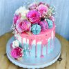 Luxury pink and blue handmade birthday cake with fresh pink and blue flowers and macarons